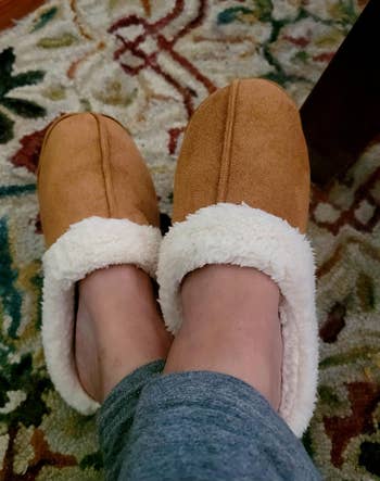 Person wearing cozy slippers in brown on carpeted floor