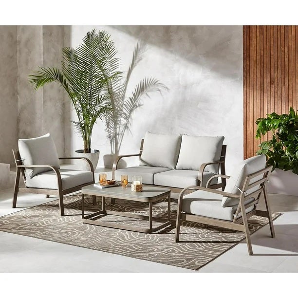 2 outdoor chairs and 1 outdoor couch in light colour, around a table