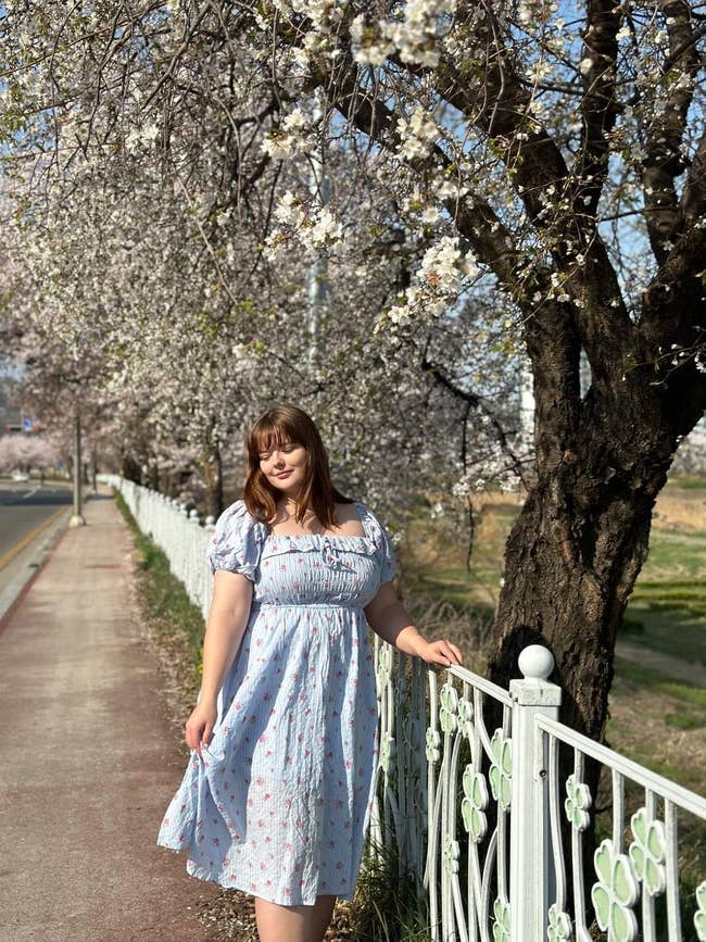 Person successful  a floral formal  stands by a blossoming tree-lined path, creating a serene springtime vibe