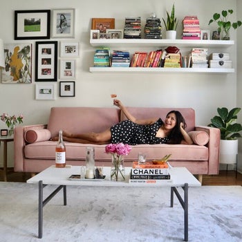 reviewer laying on the pink couch with a glass of wine