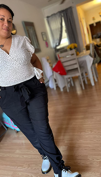 reviewer wearing the black pants with a polka dotted top and white shoes
