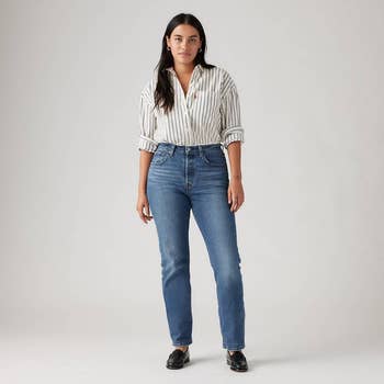 model successful  striped garment  and jeans lasting  against plain background, modeling casual attire for a buying  article