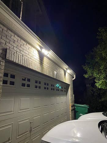 reviewer photo of the lit motion sensor lights at night, which are mounted above a garage door