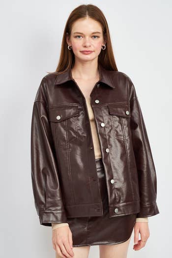 model posing in oversized brown faux leather jacket