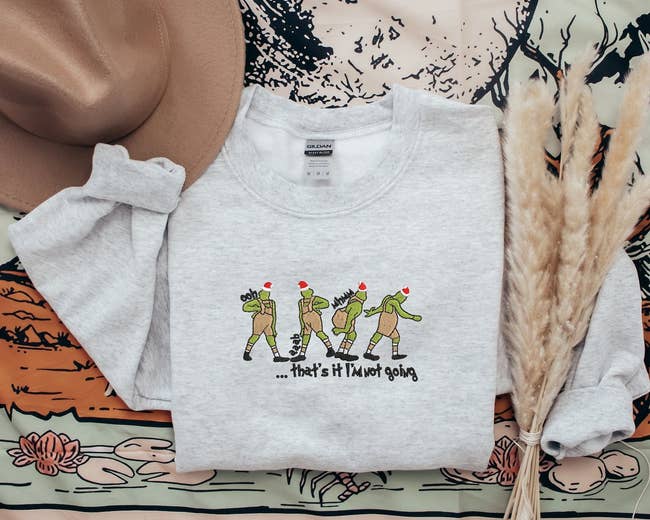 sweater with illustration of the Grinch posing in outfit