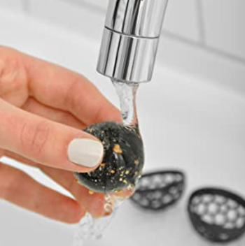 person cleaning dirty ball in sink