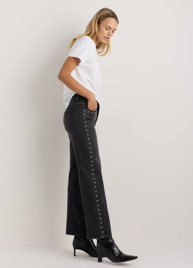 Woman successful  casual outfit with achromatic  t-shirt, wide-leg jeans, and studded details connected  the side, wearing achromatic  ankle boots