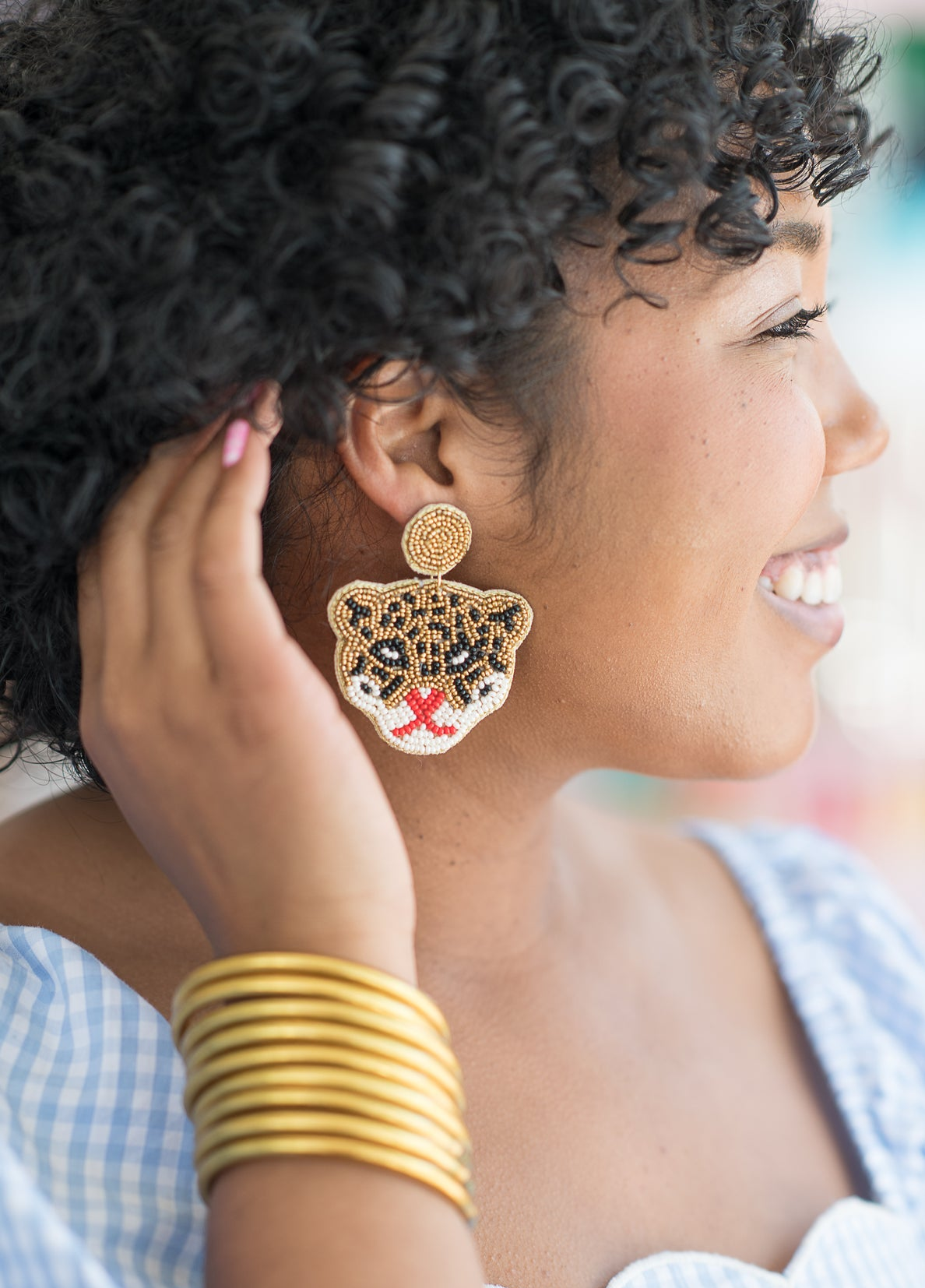 business owner modeling large beaded leopard face earrings