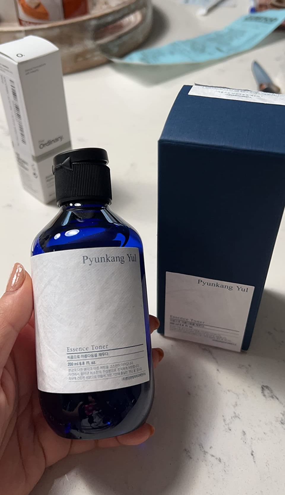 a hand holding the facial essence toner