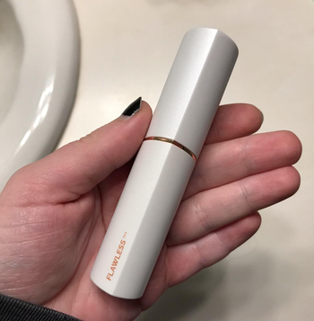 reviewer holding the white hair remover, which looks like a large tube of lip gloss