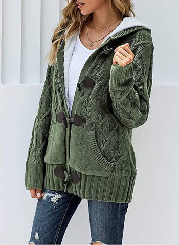 a model wearing a green knit cardigan with blue jeans