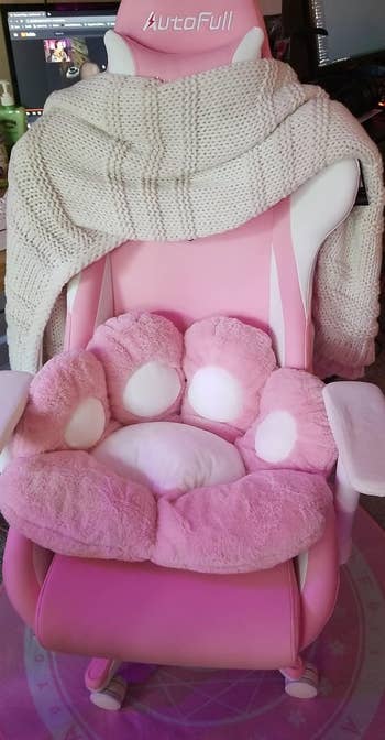 Pink gaming chair with a cozy blanket and paw cushion on the seat 