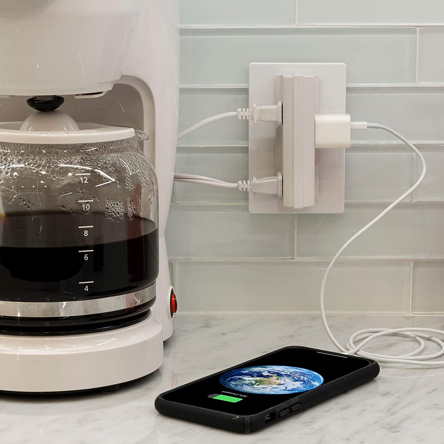 An adapter plugged into an outlet with a phone and two kitchen appliances plugged into it 