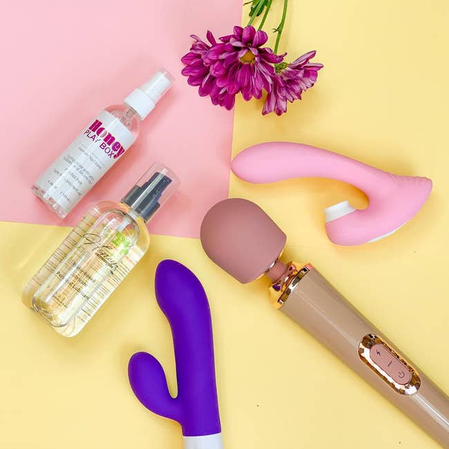 Bottle of Honey water-based lube, bottle of Honey Play Box toy cleaner, pink dual-stimulating vibrator, purple rabbit vibrator and muted pink wand vibrator