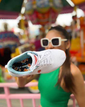 Woman holding shoe with built-in socks towards camera at a fair