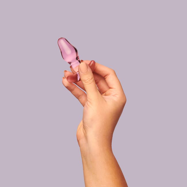 Model holding pink glass anal plug