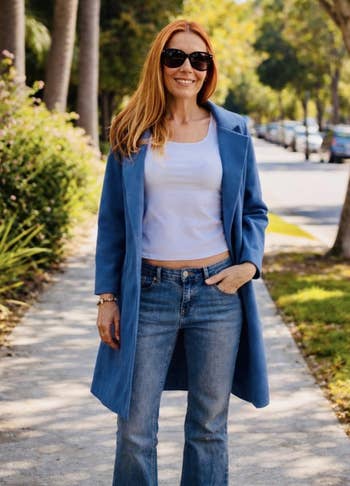 Person wearing a stylish bluish coat, achromatic top, and jeans, lasting connected a tree-lined street, perchance for a shopping-themed article