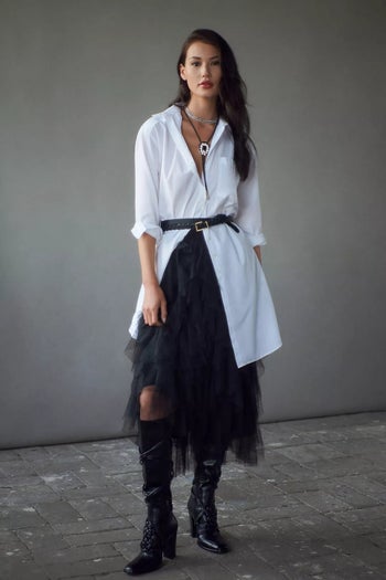 model with long button down belted over the black skirt