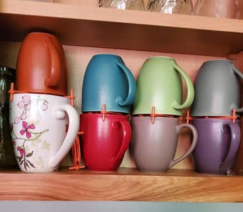 reviewer's coffee mugs in a cabinet stacked on top of each other with the orange organizers