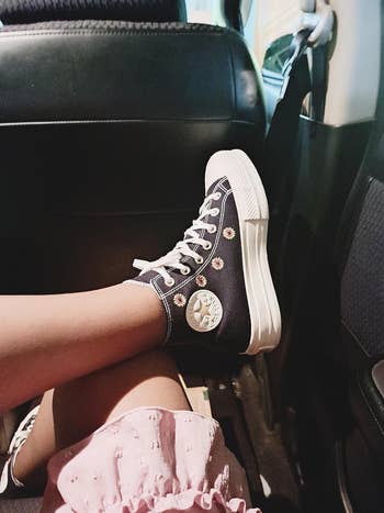 reviewer wearing black Converse sneakers with flowers embroidered