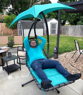 Person relaxing in a patio swing chair with canopy