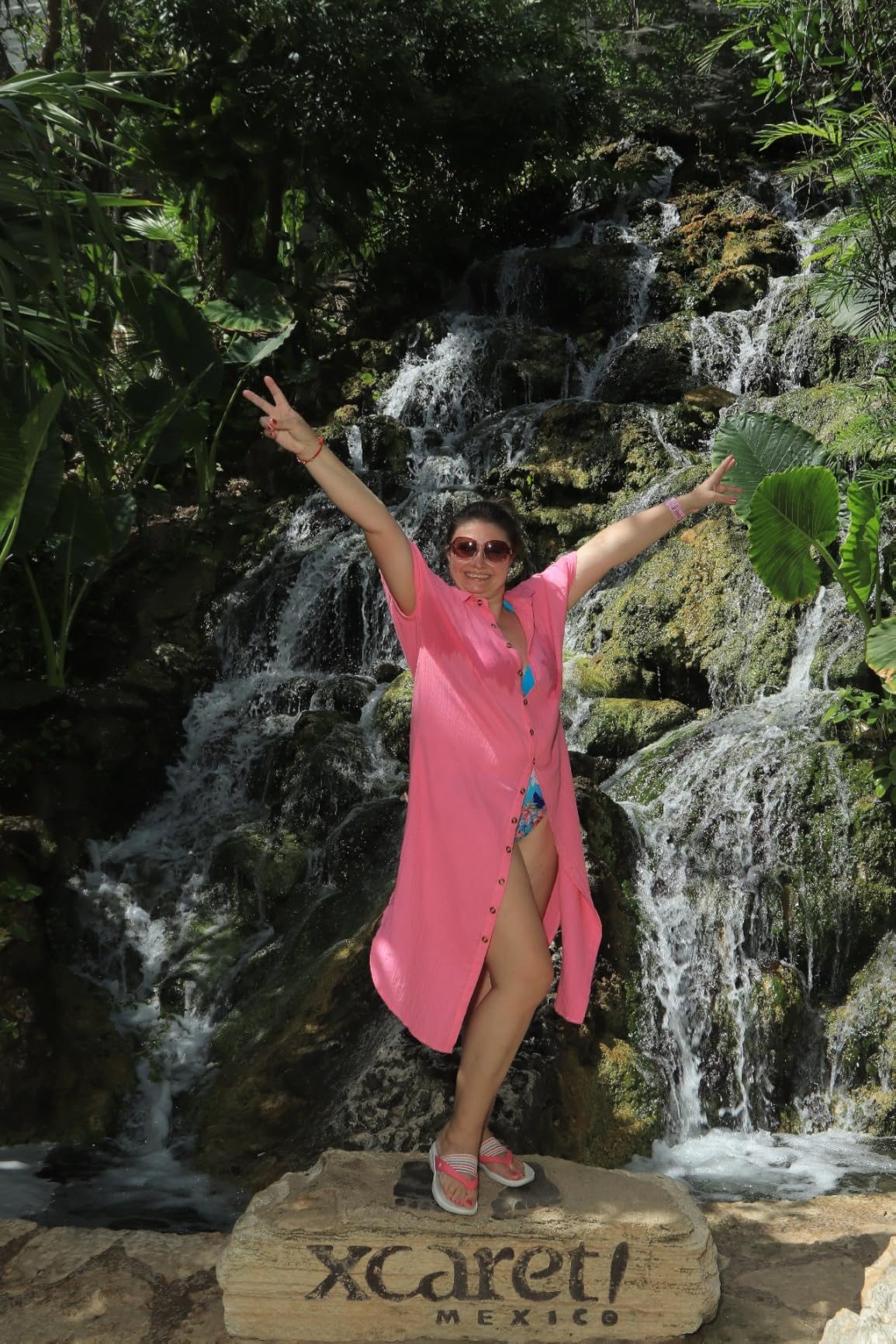 Person successful  a casual formation  outfit poses with arms raised adjacent   a waterfall successful  Xcaret, Mexico