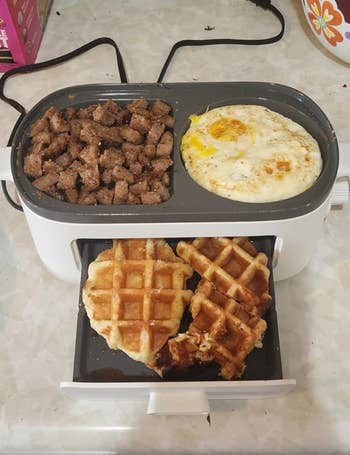 Cooked steak cubes, fried egg, and a waffle on a reviewer's divided electric grill
