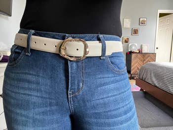 Person wearing bluish  jeans and a achromatic  loop  with a ample  circular  buckle lasting  successful  a bedroom