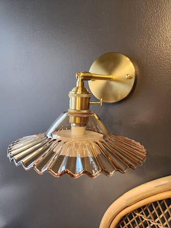 A brass partition  airy  fixture with a ribbed solid  shade, mounted supra  a rattan chair