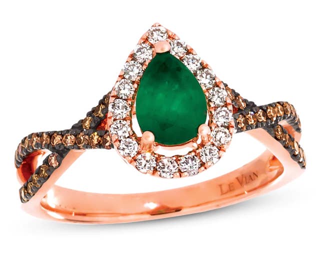 The emerald pear cut stone surrounding by small white stones and the criss cross band has chocolate diamonds throughout