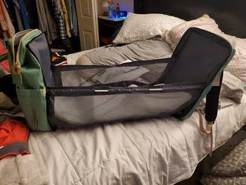 reviewer showing how the diaper bag opens to create a changing or nap area
