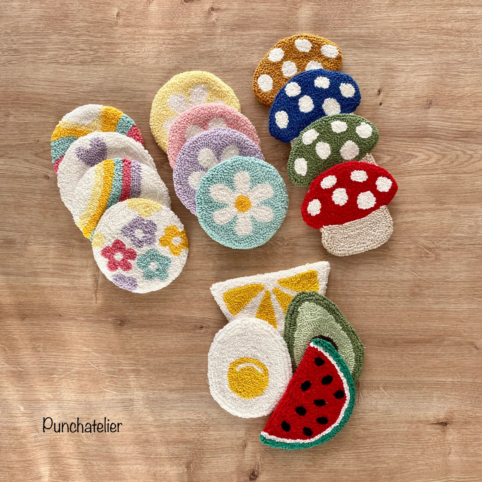 Colorful, handmade coasters featuring floral, fruit, and mushroom designs arranged on a wooden surface
