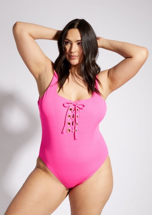 model in hot pink one piece with gold grommets and lace up detail
