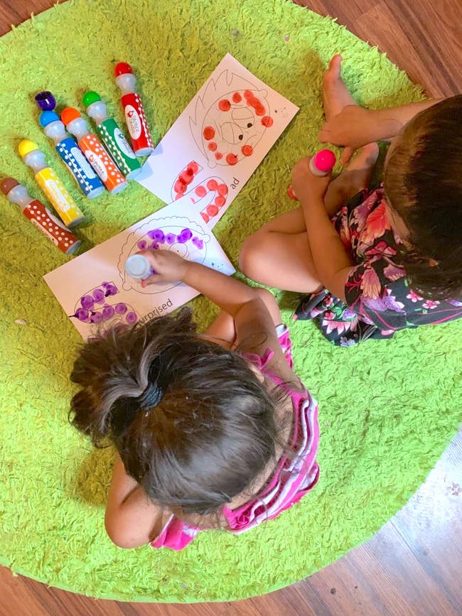 two toddlers using the dot markers on paper