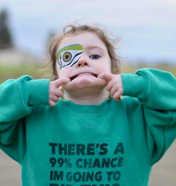 Child with eye patch pulling a funny face, shirt with humorous text about removing the patch