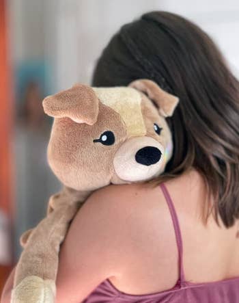 Model hugging a medium sized brown dog plush 