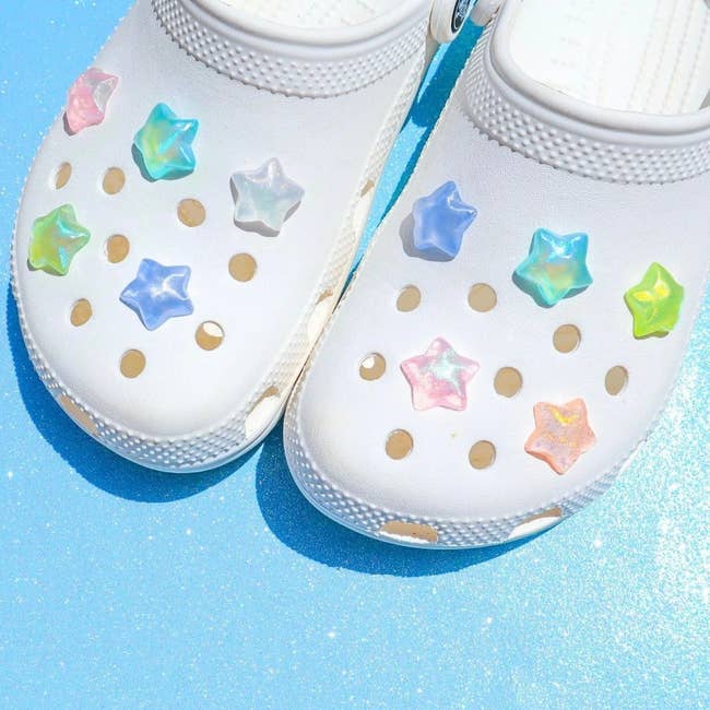 White clogs adorned with star-shaped charms connected  a glittering surface, featured successful  a buying  article