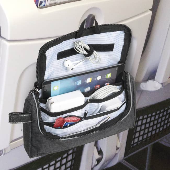 The pouch hanging on the back of a chair on a plane filled with items