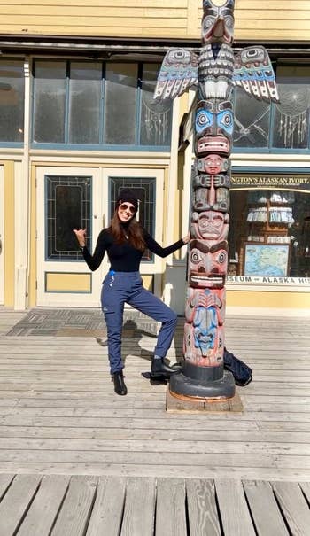 Person smiling successful casual attire, leaning connected a decorative totem rod extracurricular a gathering with ample windows. Perfect for outdoor escapade shopping