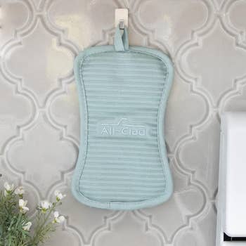 the light blue pot holder hanging on the wall using the attached loop