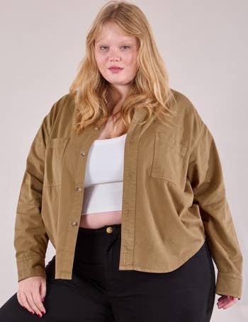 Person wearing a casual, unbuttoned brownish  garment  implicit    a achromatic  vessel  apical  and achromatic  pants, lasting  confidently