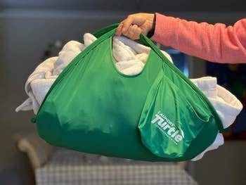 a reviewer holding the turtle with a bunch of laundry inside