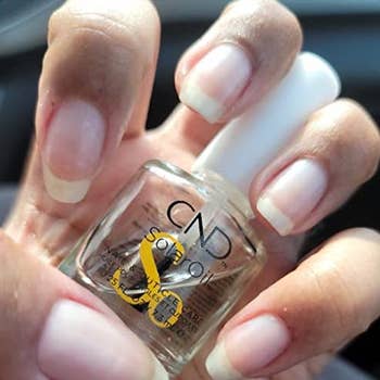 reviewer holding a bottle of the cuticle repair oil