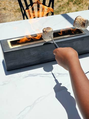 reviewer roasting marshmallows over tabletop fire pit