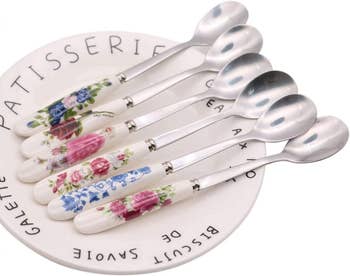 Set of ceramic-handled teaspoons with floral design on a saucer labeled 