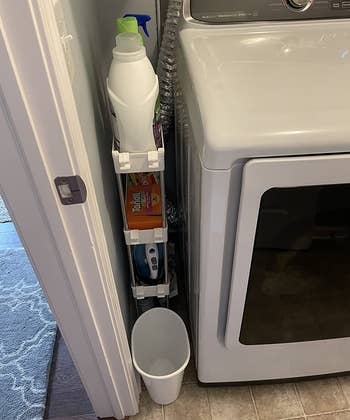 a reviewer photo of the storage rack tucked between a wall and a washing machine 