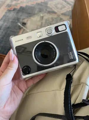 Person holding a Fujifilm Instax Mini 90 instant camera with a classical  design