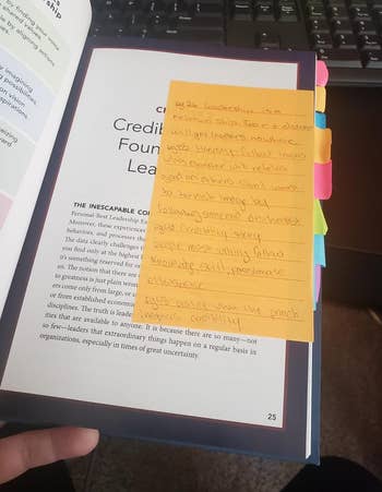 Open book with multiple colored sticky notes containing handwritten notes 