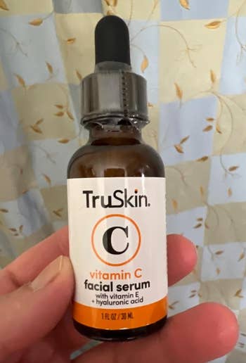 Hand holding a TruSkin Vitamin C facial serum bottle with dropper