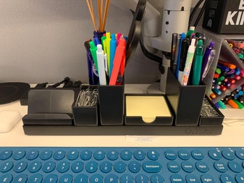 the organizer on a reviewer's desk holding pens, paper clips, sticky notes and more